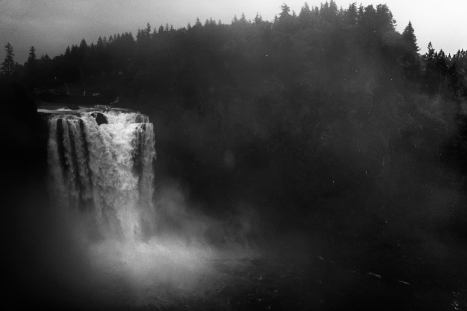 Snoqualmie Falls in mist with trees beside the falling water.