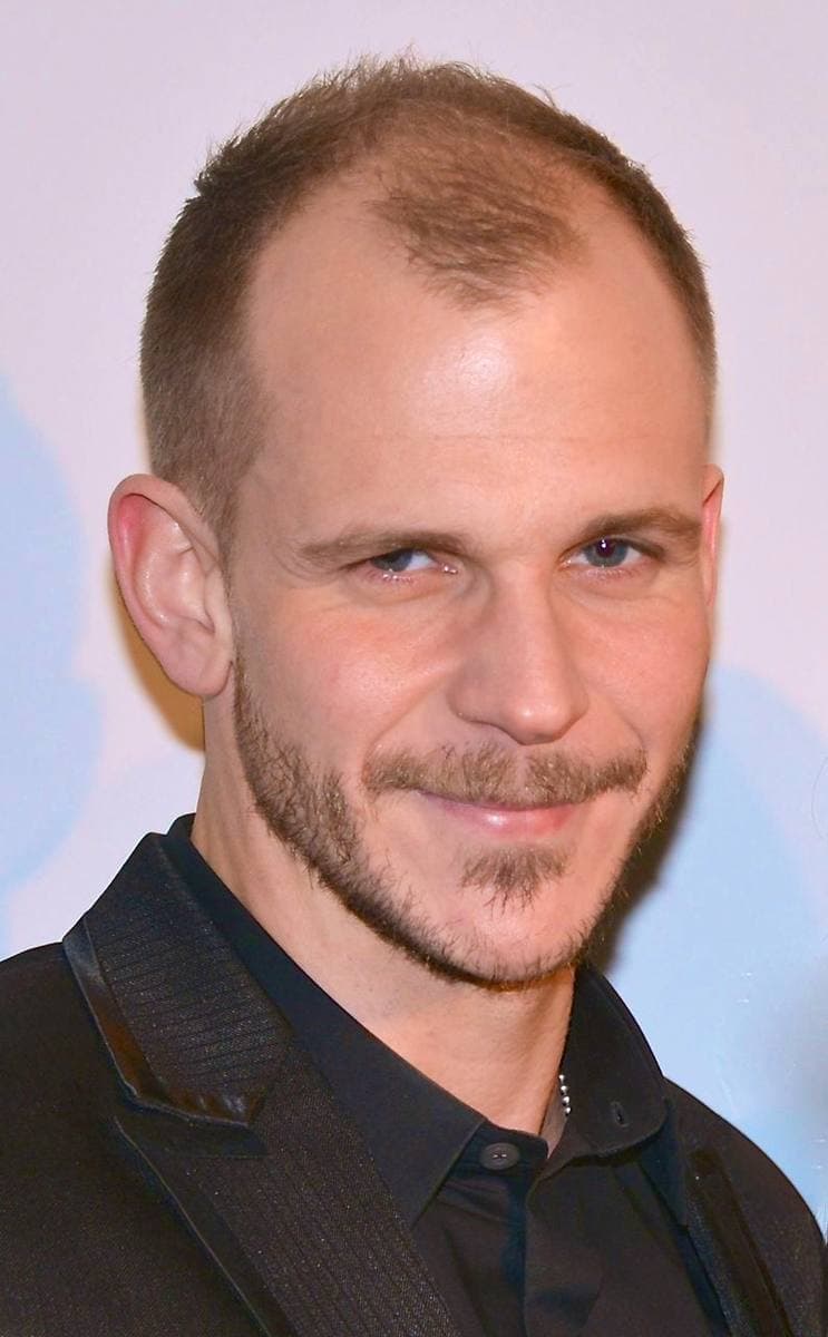 Gustaf Skarsgård in a dark suit, smiling slightly