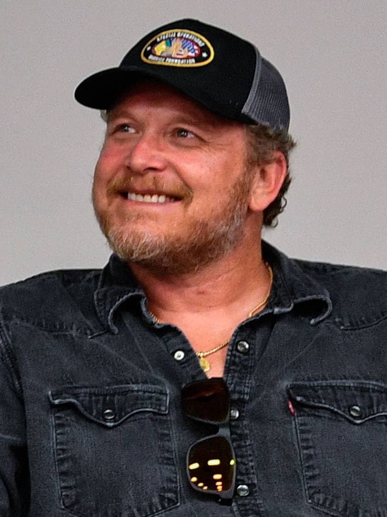 Cole Hauser in a cap and denim shirt, smiling