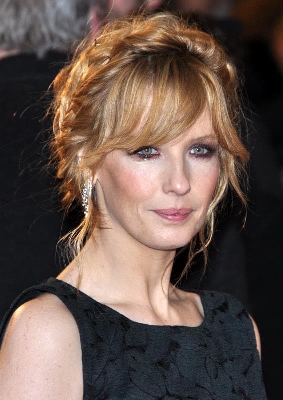 Kelly Reilly with red-gold hair pinned up, smiling, in a black dress
