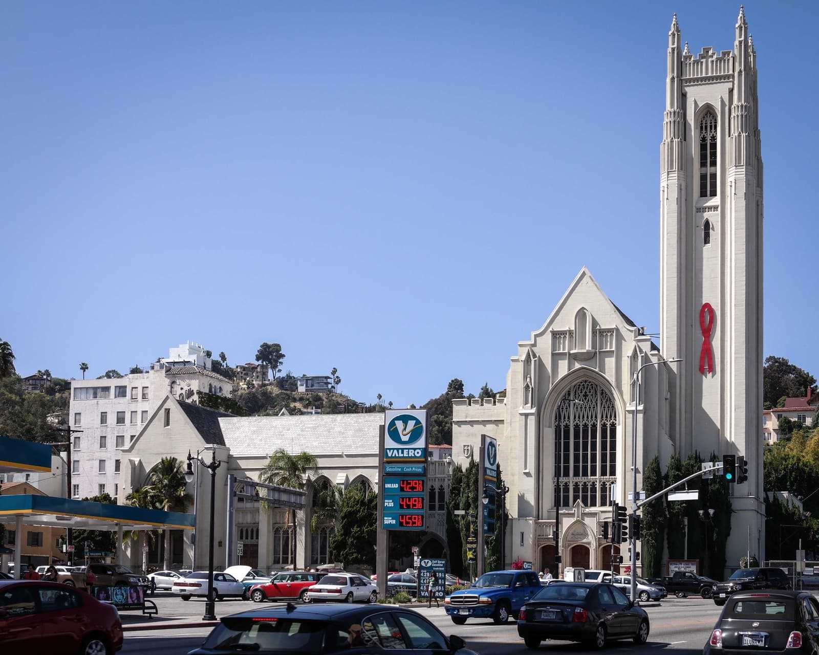 A white Gothic church tower rising above a busy Hollywood junction