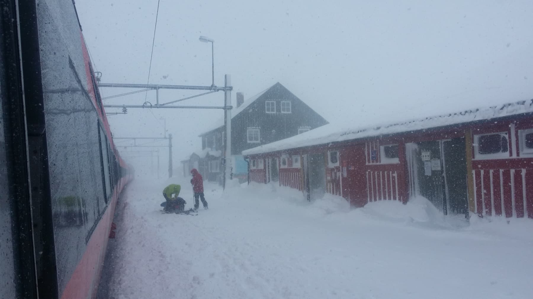 Snow blowing across a white plateau with buildings barely visible