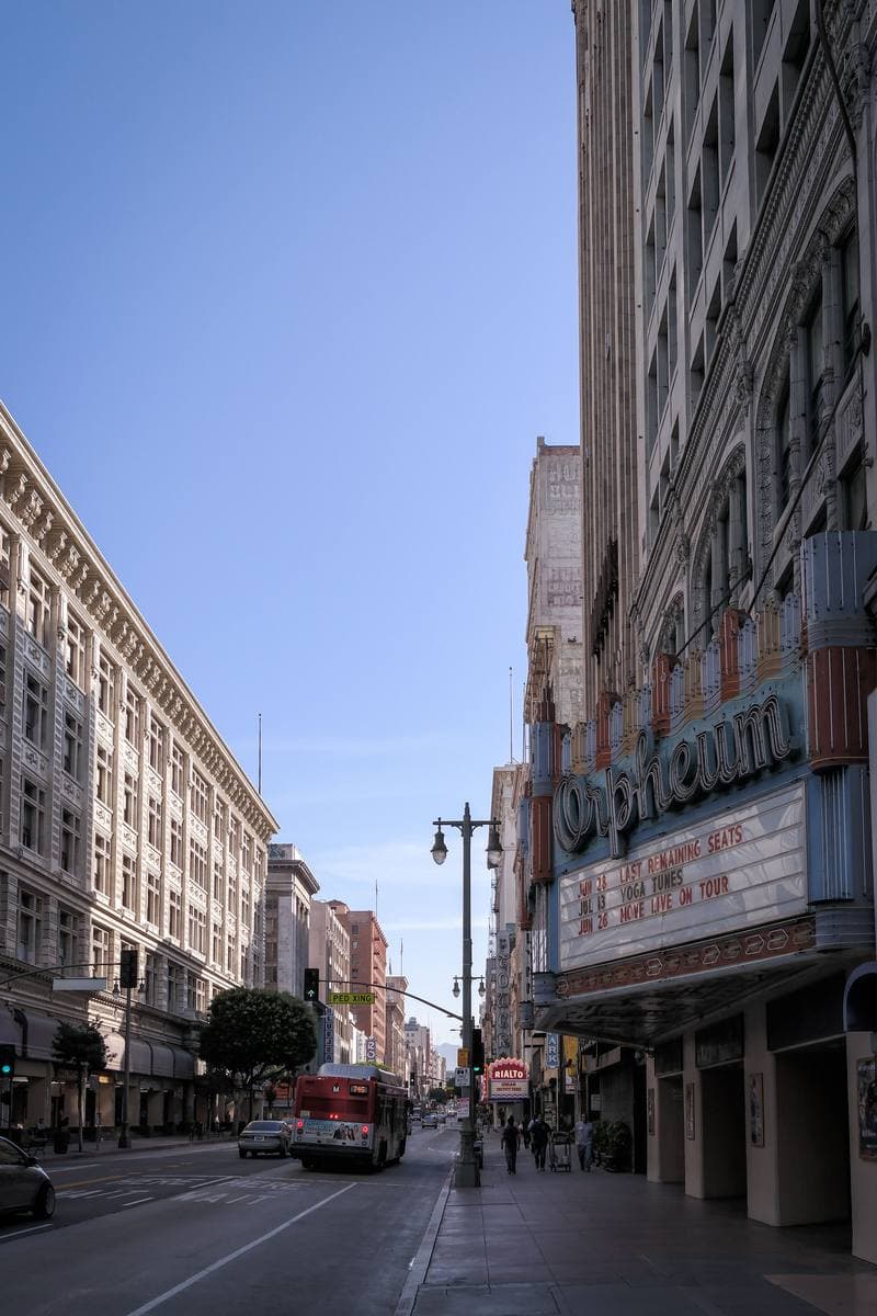 A long view down Broadway with a theatre marquee on the right and old buildings beyond