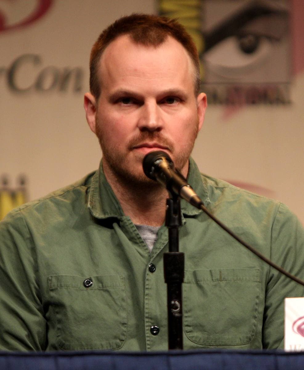 Marc Webb, in a green shirt, speaking into a microphone at a panel table