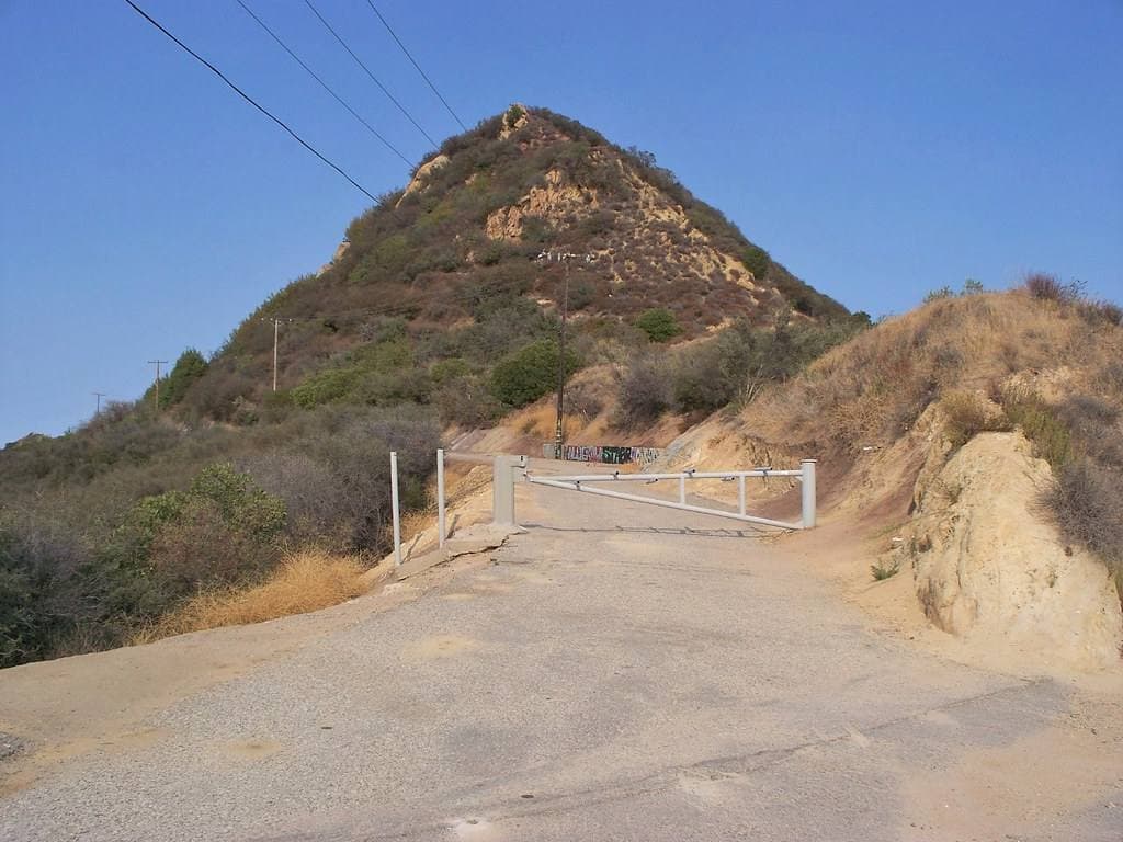 A gated dirt track below a scrubby peak in the Santa Monica Mountains