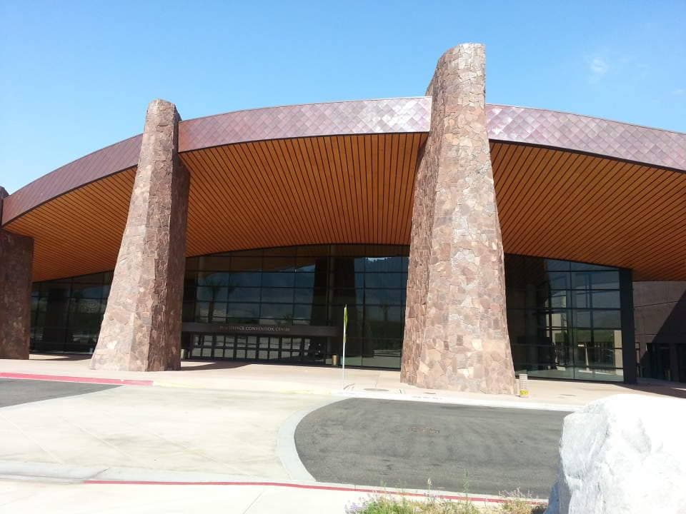 Two tall copper-brown pylons in front of a curved glass and metal building