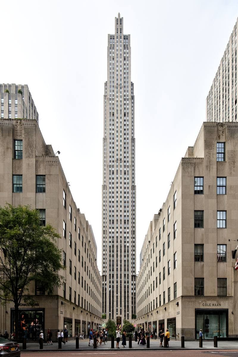 The stepped limestone tower of 30 Rockefeller Plaza rising between lower buildings