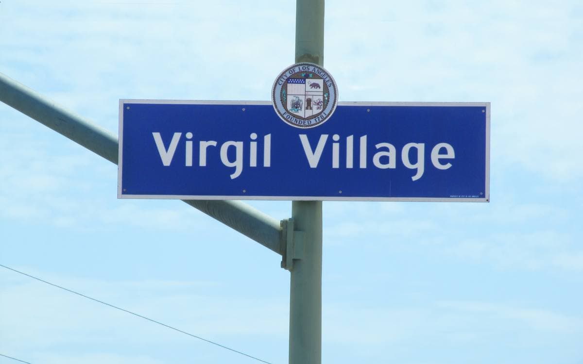 A blue Los Angeles street sign reading Virgil Village against a pale sky
