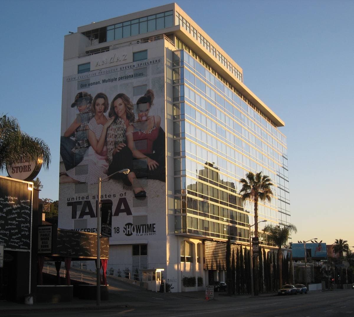 A tall white hotel block with glassed-in balconies and a giant billboard on its side