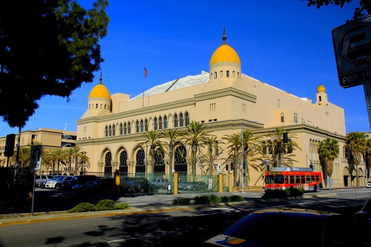 A Moorish-style auditorium with domes and towers under a blue sky