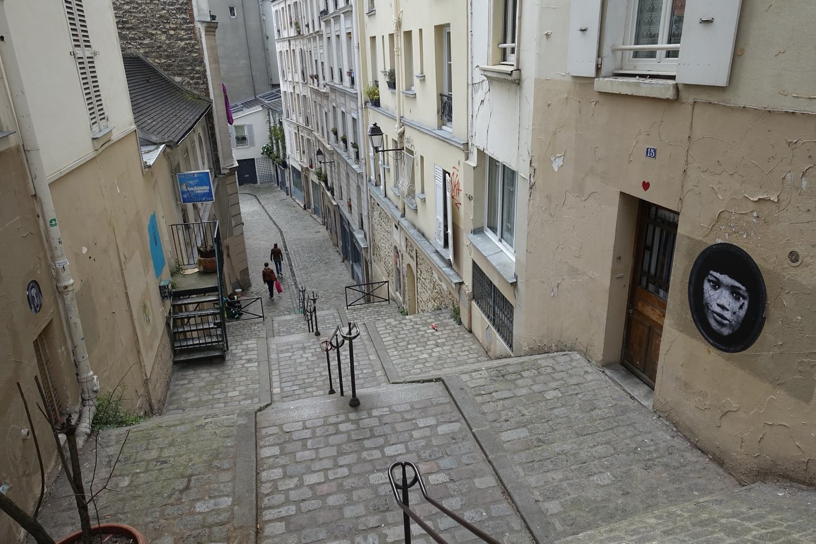 Steep stone steps with handrails running down between plain Montmartre houses
