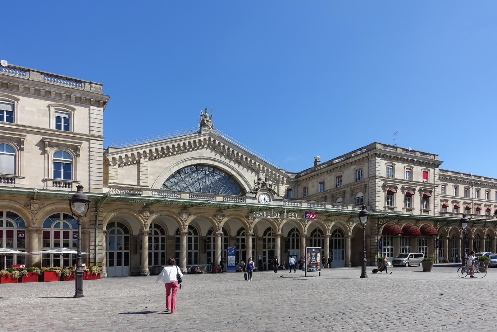 The stone façade of the Gare de l'Est with its great arched window, and a cobbled forecourt