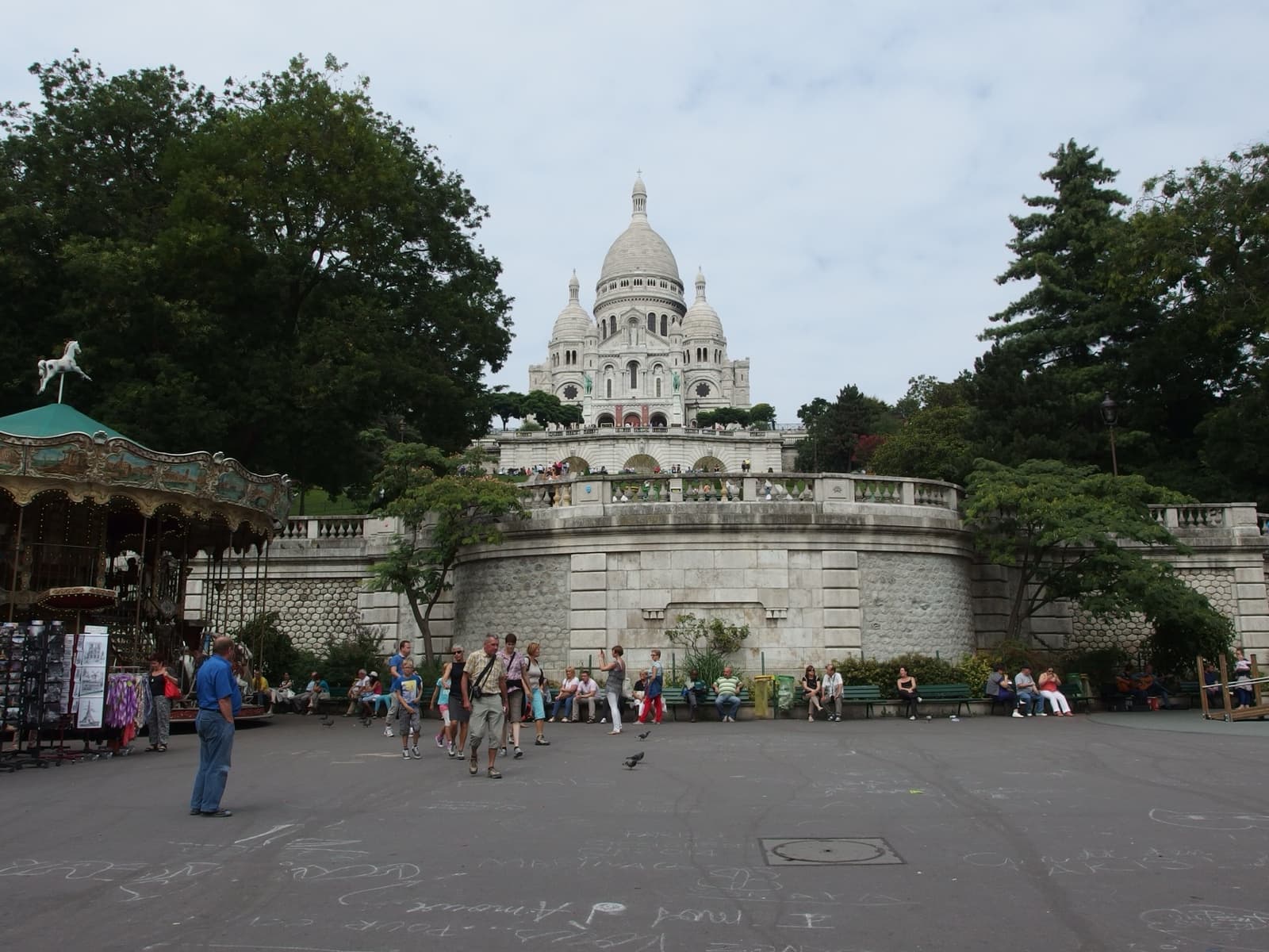 A wide square with a carousel at left, terraced gardens rising behind and the white basilica at the top