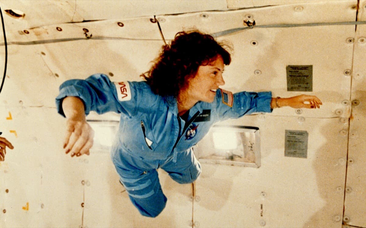 A woman floats in a padded aircraft cabin, her hair drifting upwards