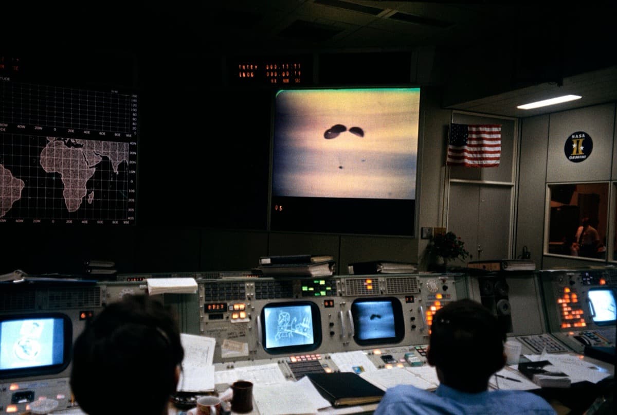 Flight controllers at consoles watching a wall of screens