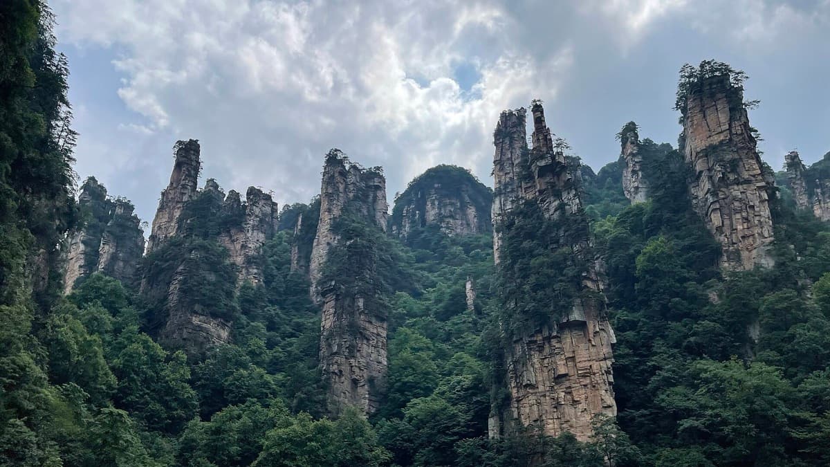 Sandstone pillars covered in trees rising out of a green valley