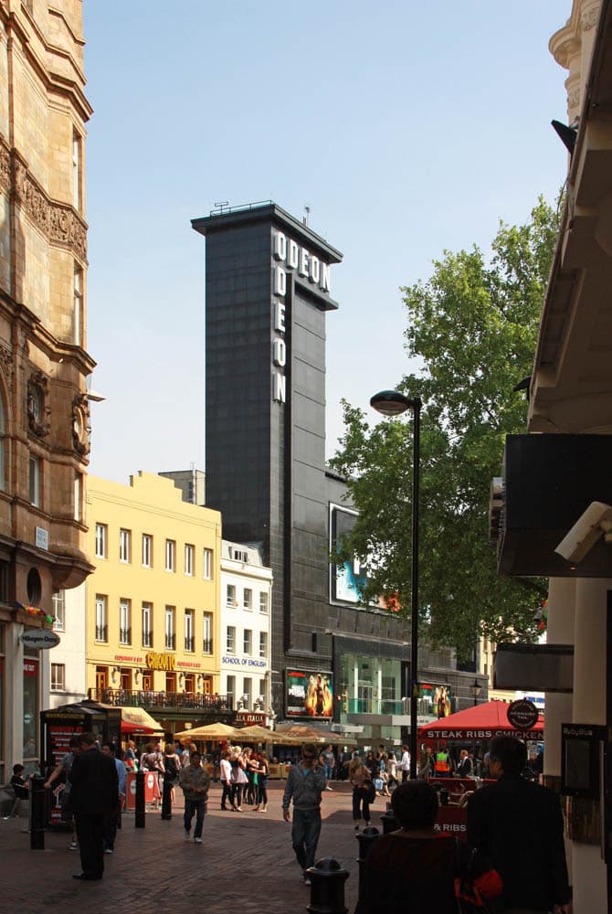 The pale tall front of a cinema on a London square