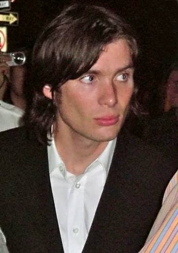 Cillian Murphy with dark hair in a dark jacket and white shirt at a night premiere