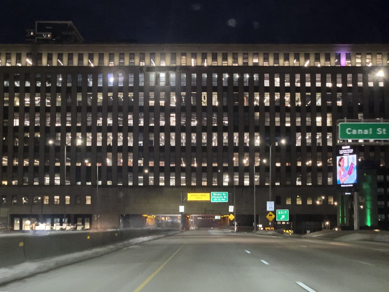 A long lit office block straddles a highway at night