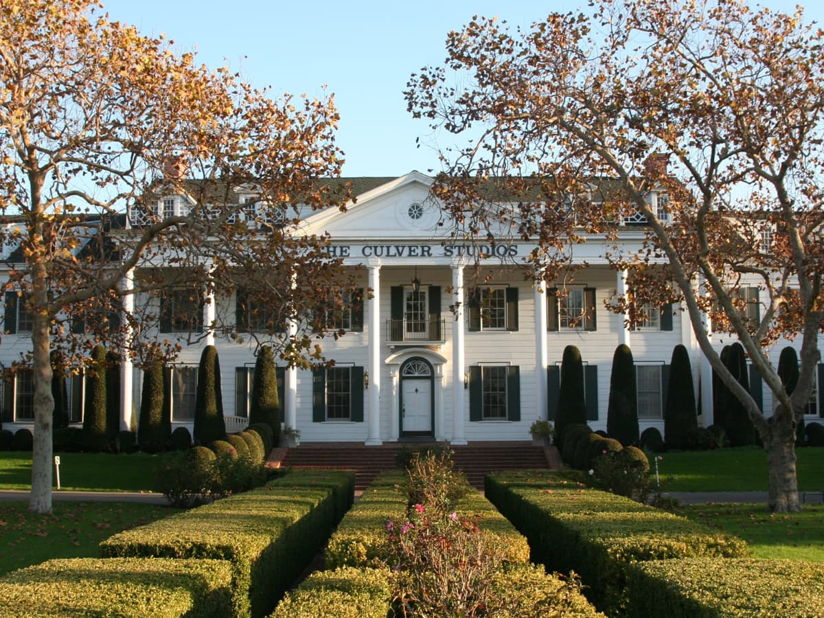 The columned white front of a studio building with a lawn