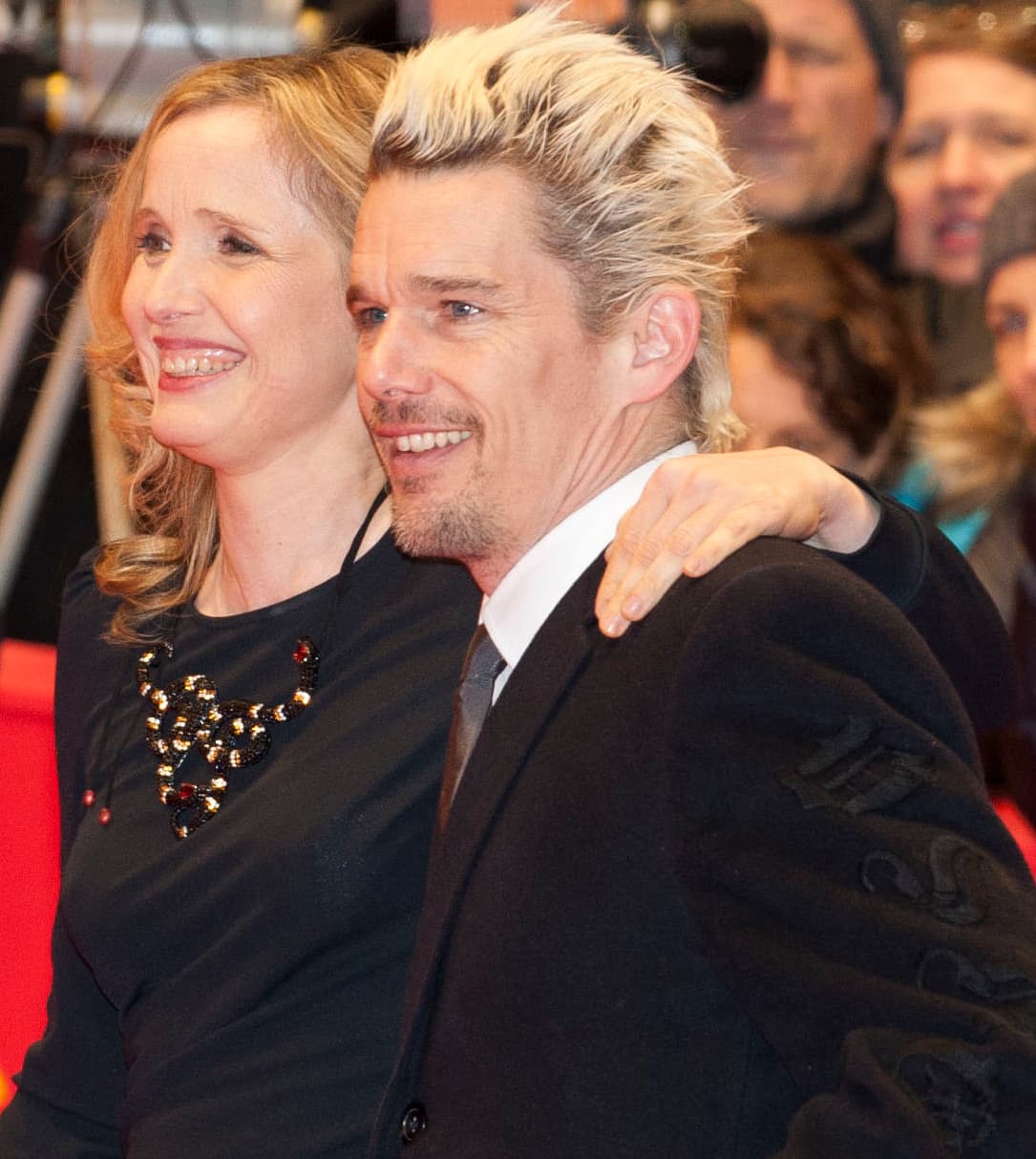 Julie Delpy and Ethan Hawke, smiling, his arm round her shoulders, on a red carpet