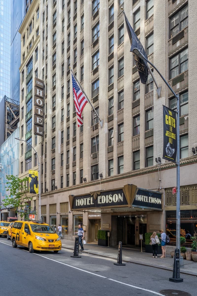 A hotel entrance under an illuminated sign and a canopy
