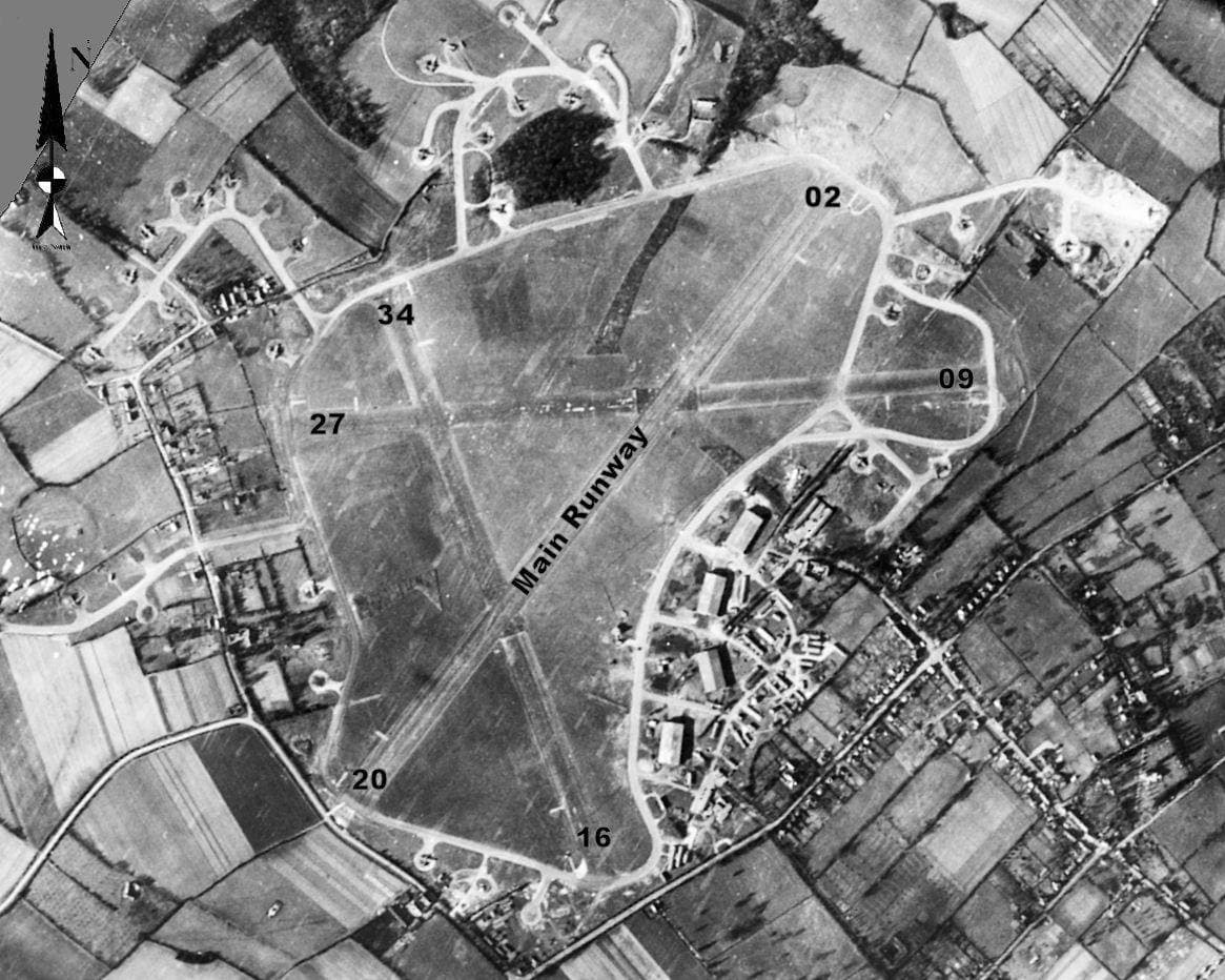 A black-and-white wartime aerial photograph of an airfield with runways