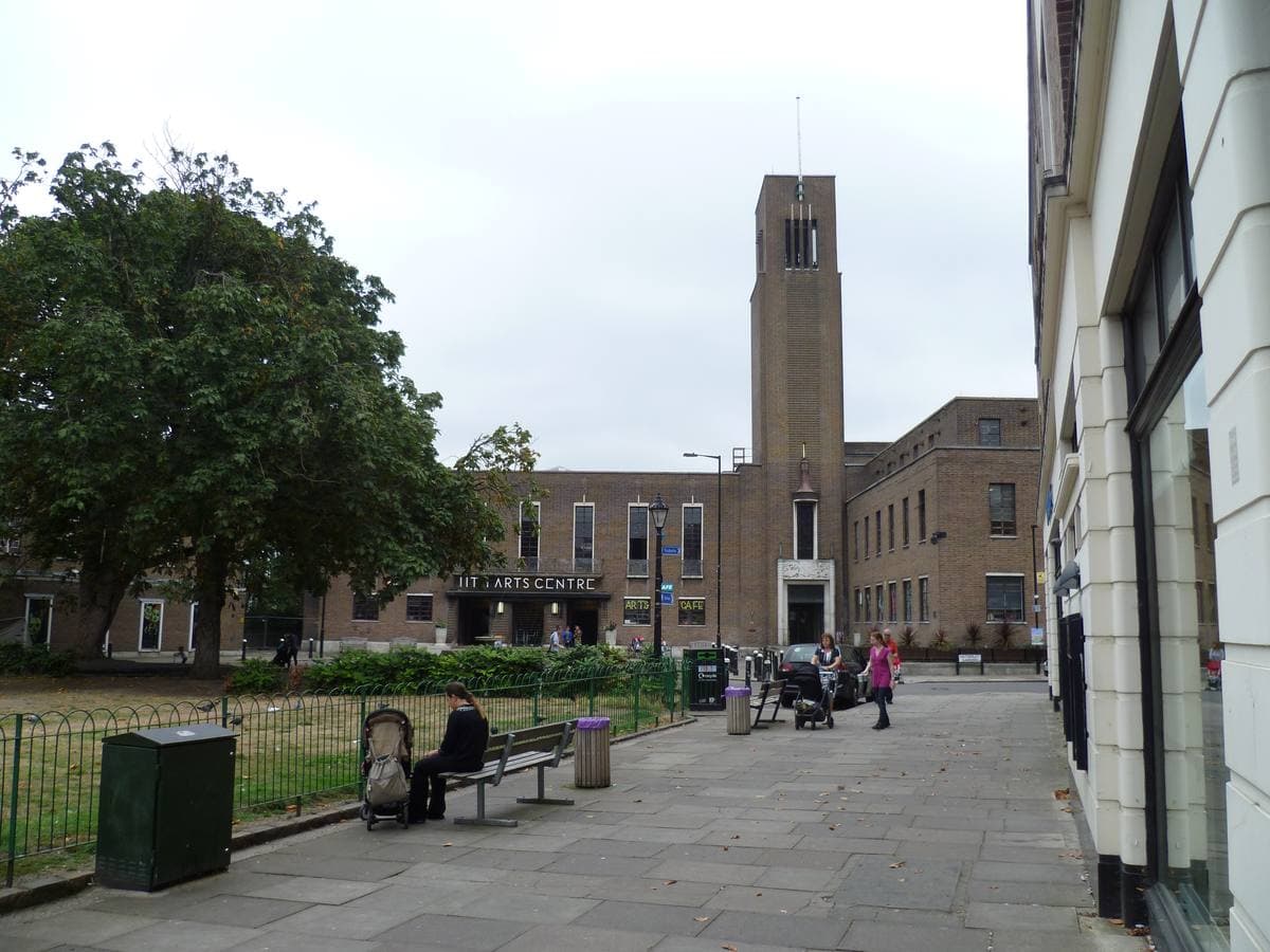 A brick 1930s town hall with a tall tower behind a square