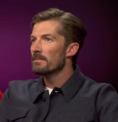 Gwilym Lee with curly hair on a television set