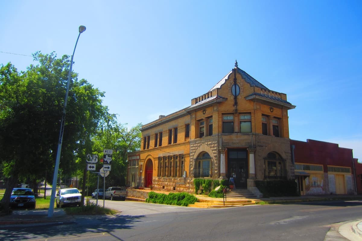 A corner brick bank building with large windows on a small-town square
