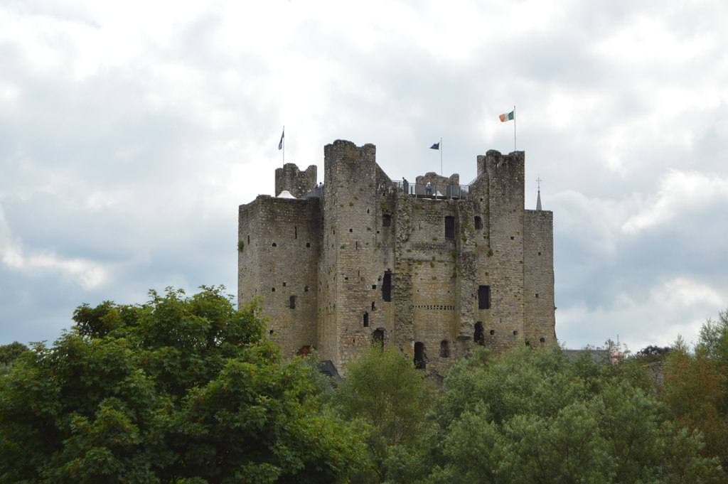 A great square stone keep with corner towers above green trees