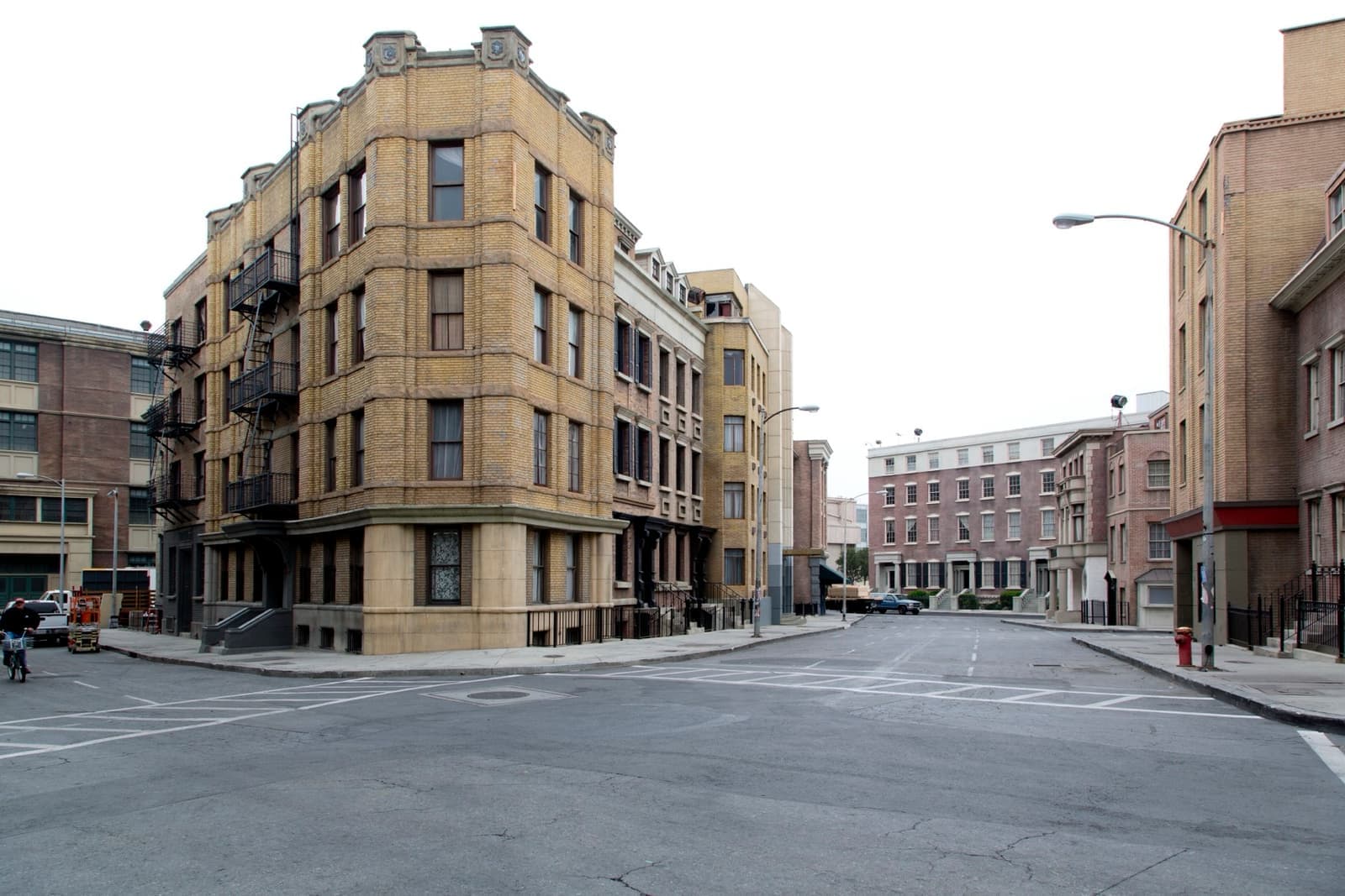 An empty street of painted brick and stone apartment-house fronts with a fire escape, built as a set