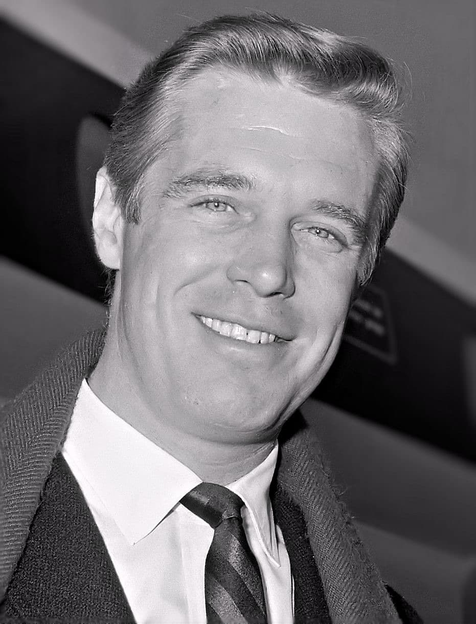 George Peppard smiling, in a tweed jacket and striped tie