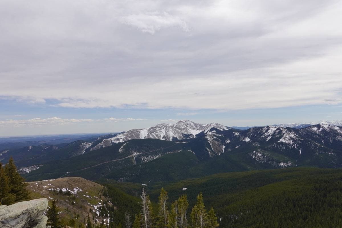 A broad rounded mountain over forested foothills