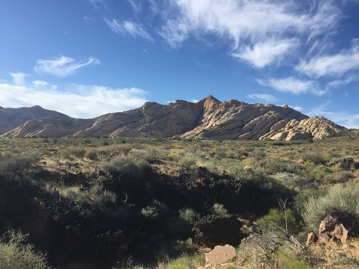 Red and white sandstone cliffs and desert scrub in Snow Canyon State Park.