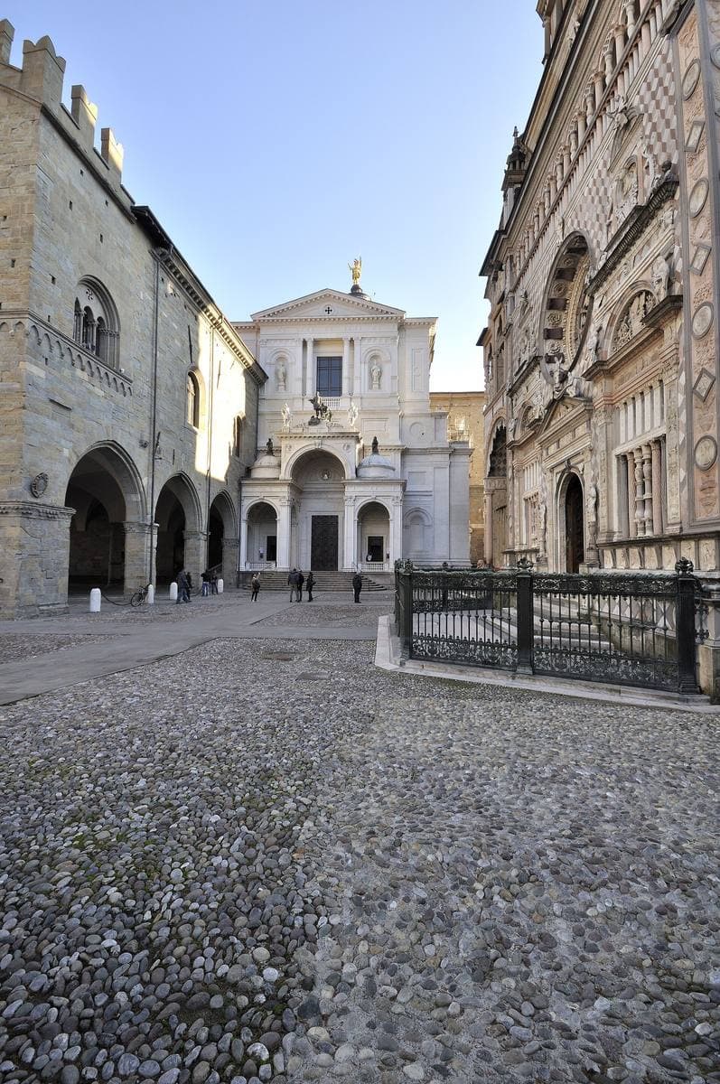 A cobbled square ringed by stone buildings, the cathedral front at the far end