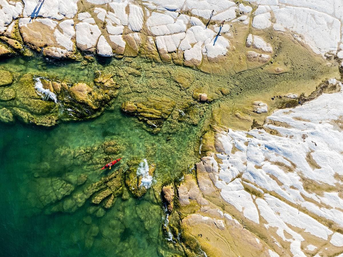 White limestone slabs and clear green water seen from the air, with a few swimmers
