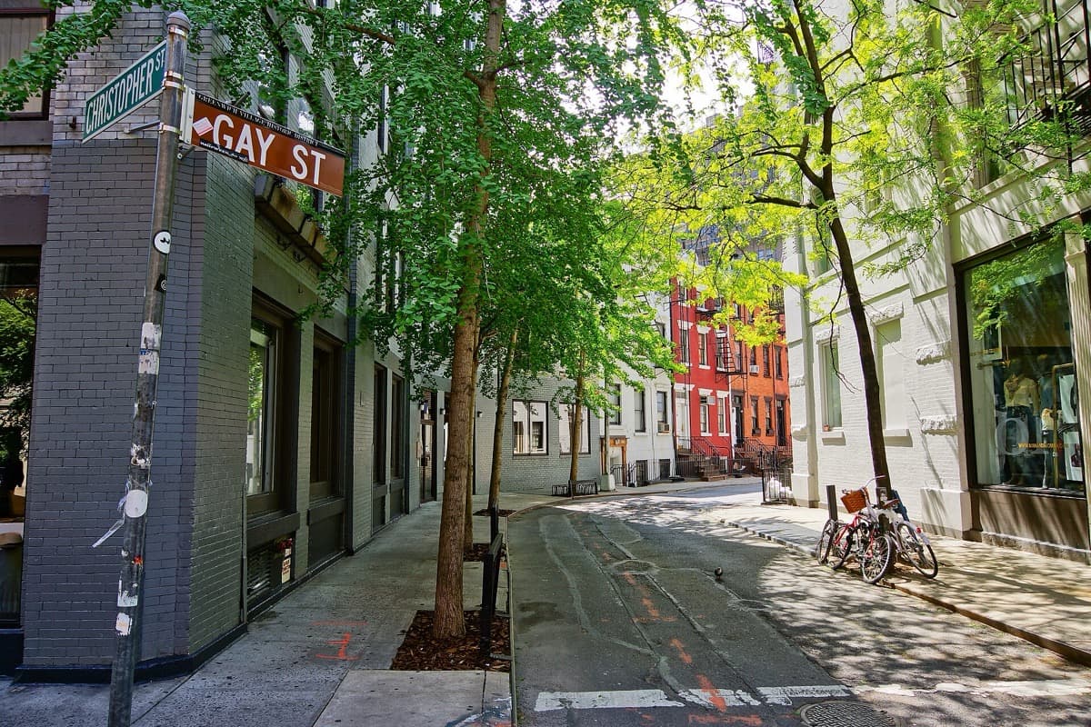 A short curved street of brick row houses with parked cars