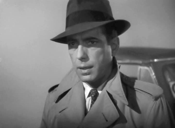 Humphrey Bogart in trench coat and fedora, night