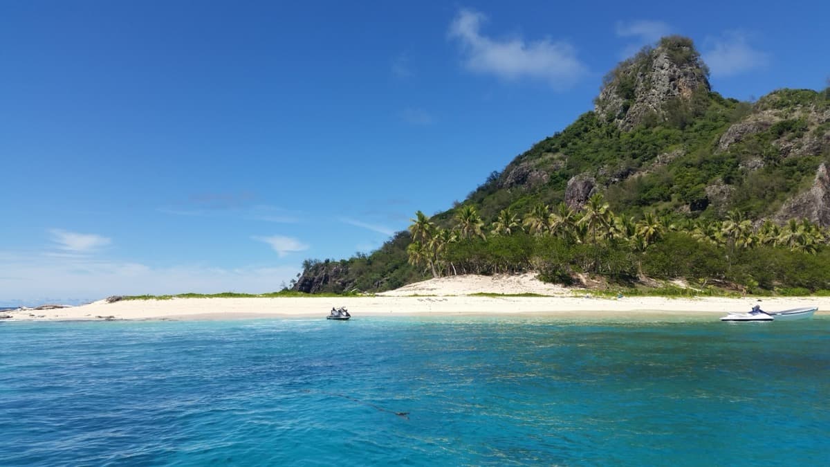 Monuriki island from the sea, a green ridge rising above a narrow beach.