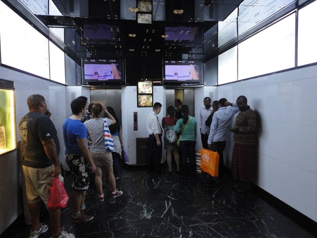 People queueing at the lifts inside Chungking Mansions, watched by a guard