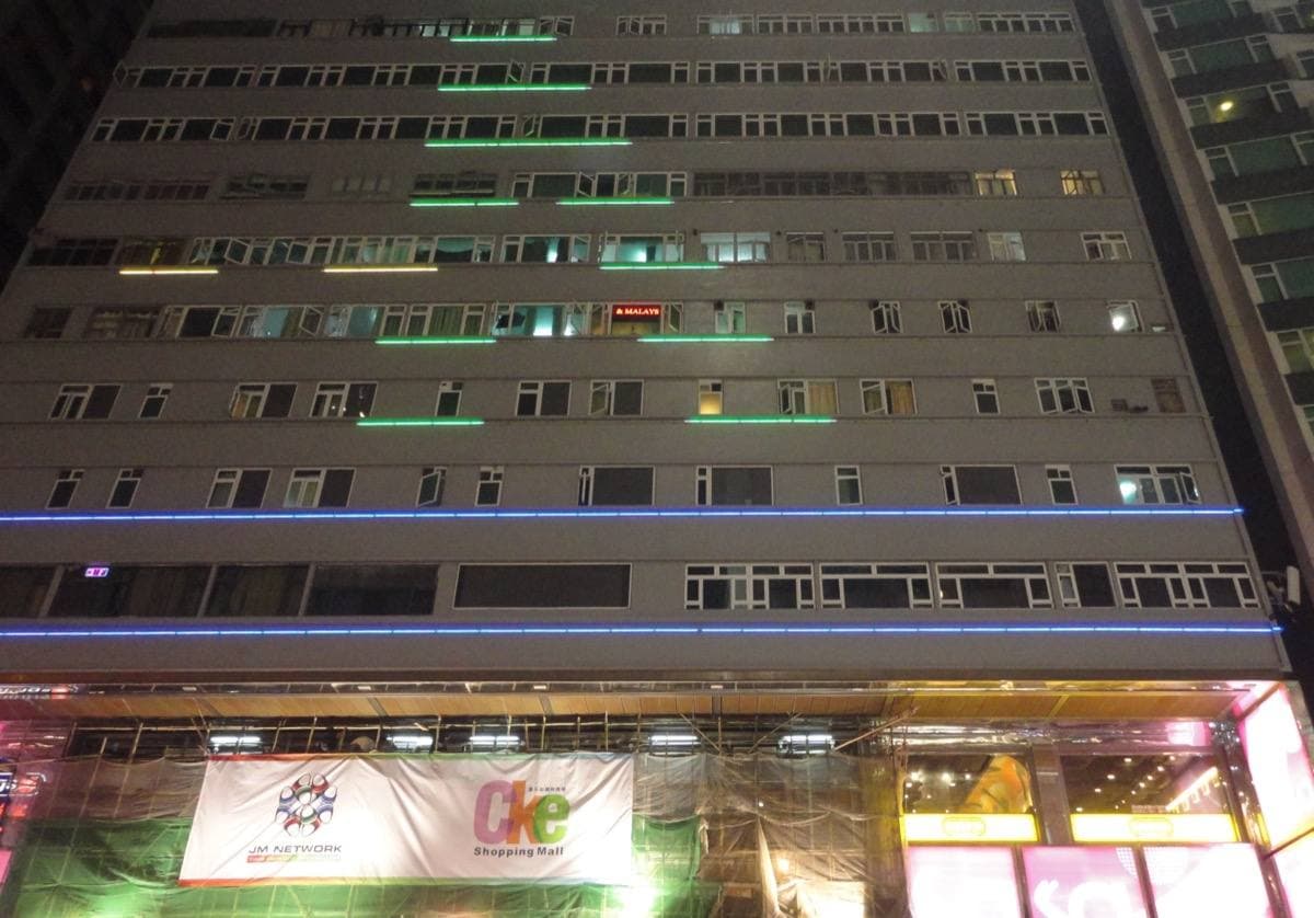 The lit entrance of Chungking Mansions on Nathan Road at night, people walking past