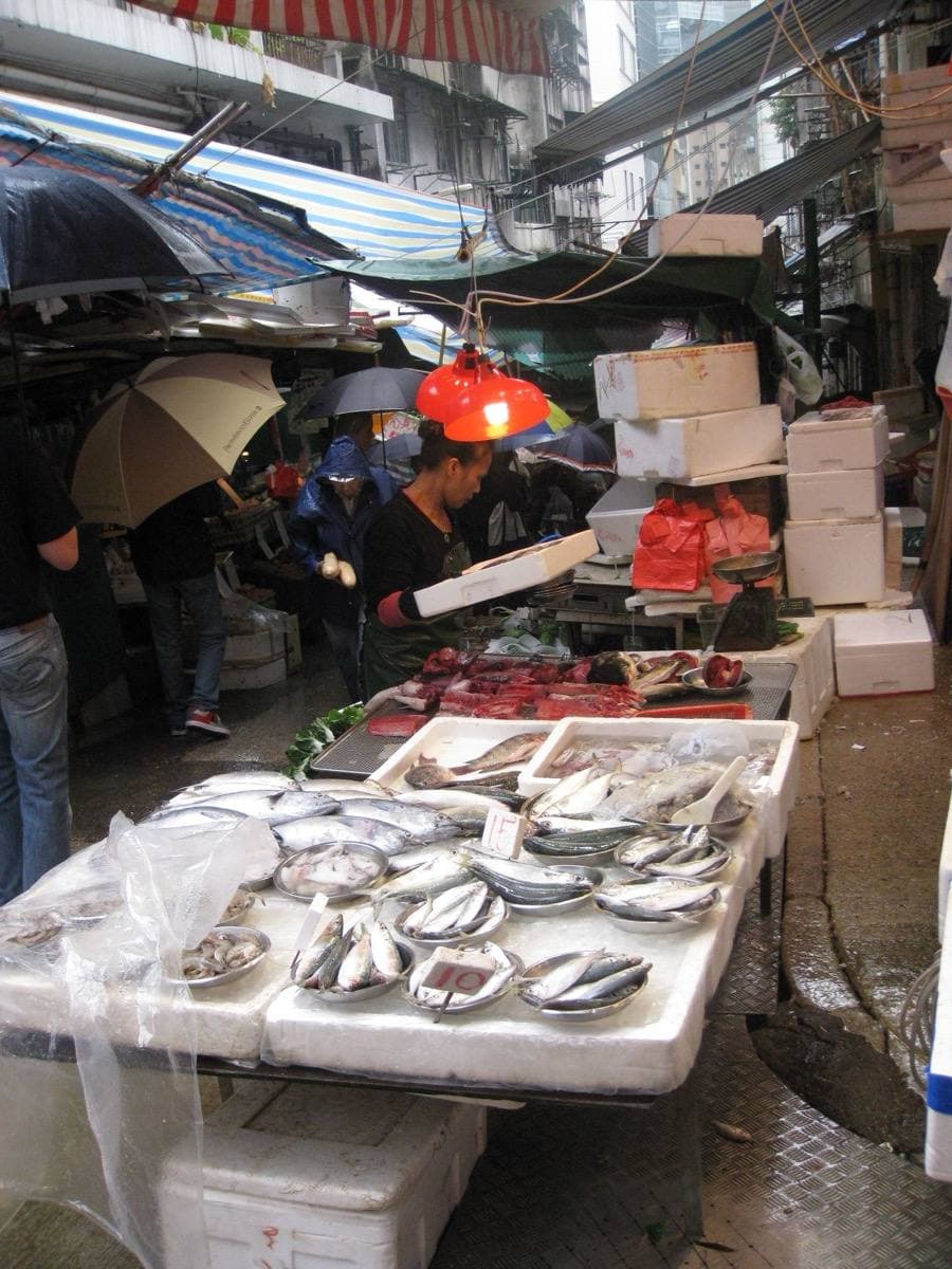 Fruit and vegetable stalls under awnings on a steep street