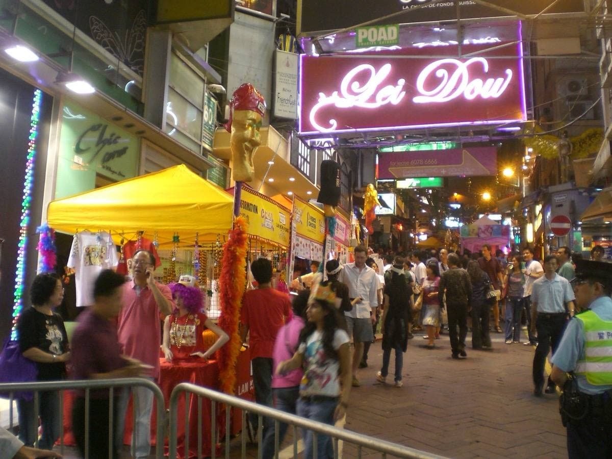 A crowd on D’Aguilar Street at night under bar signs