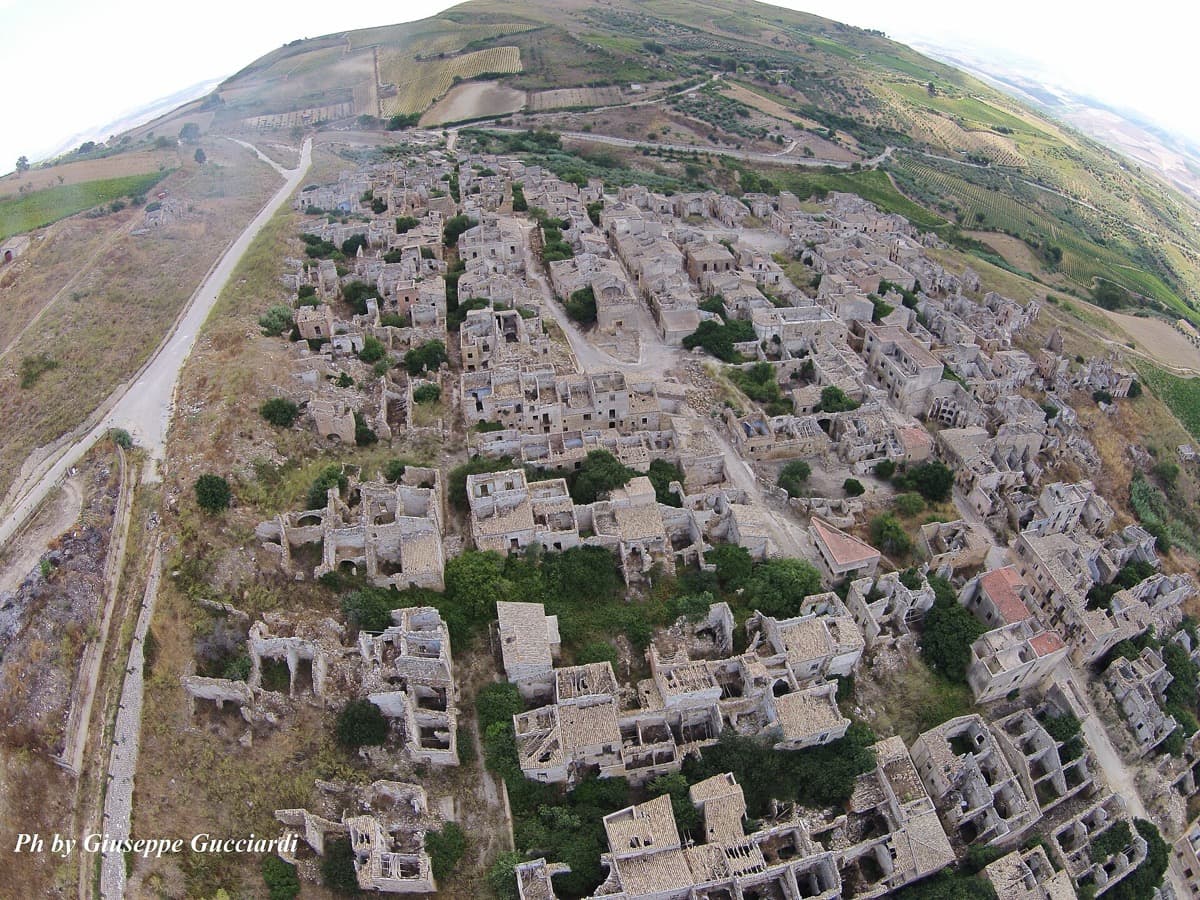 Ruined stone houses along an empty street in a hillside town