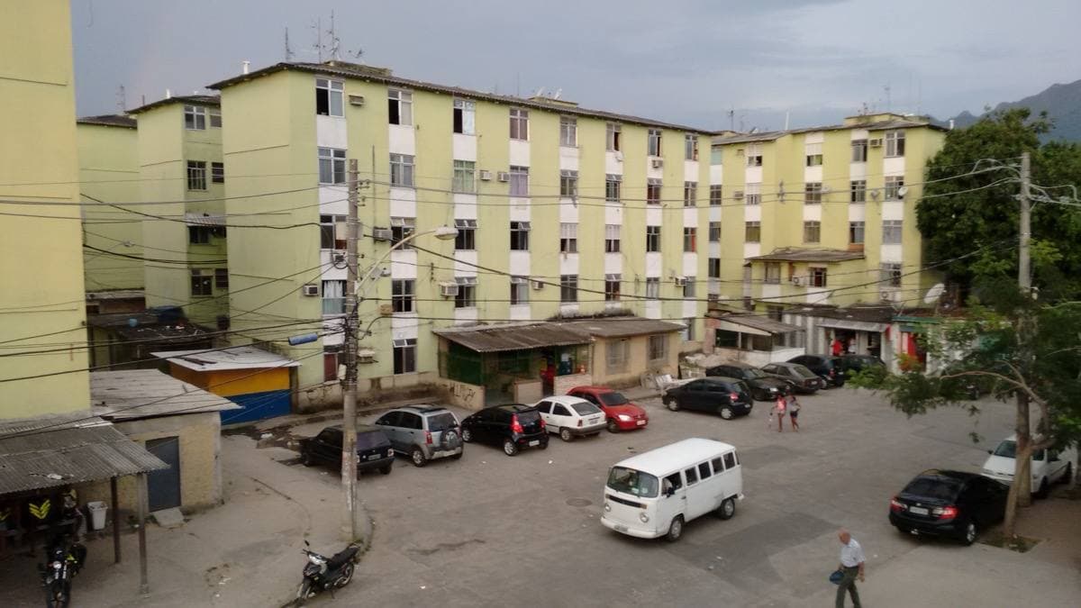 Low rooftops and streets of Cidade de Deus spreading towards green hills