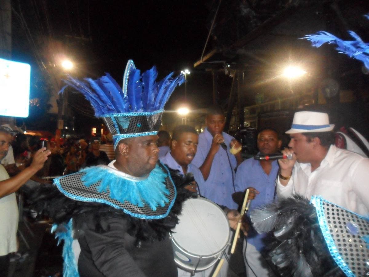 Samba school dancers in blue and white costumes at a night carnival parade