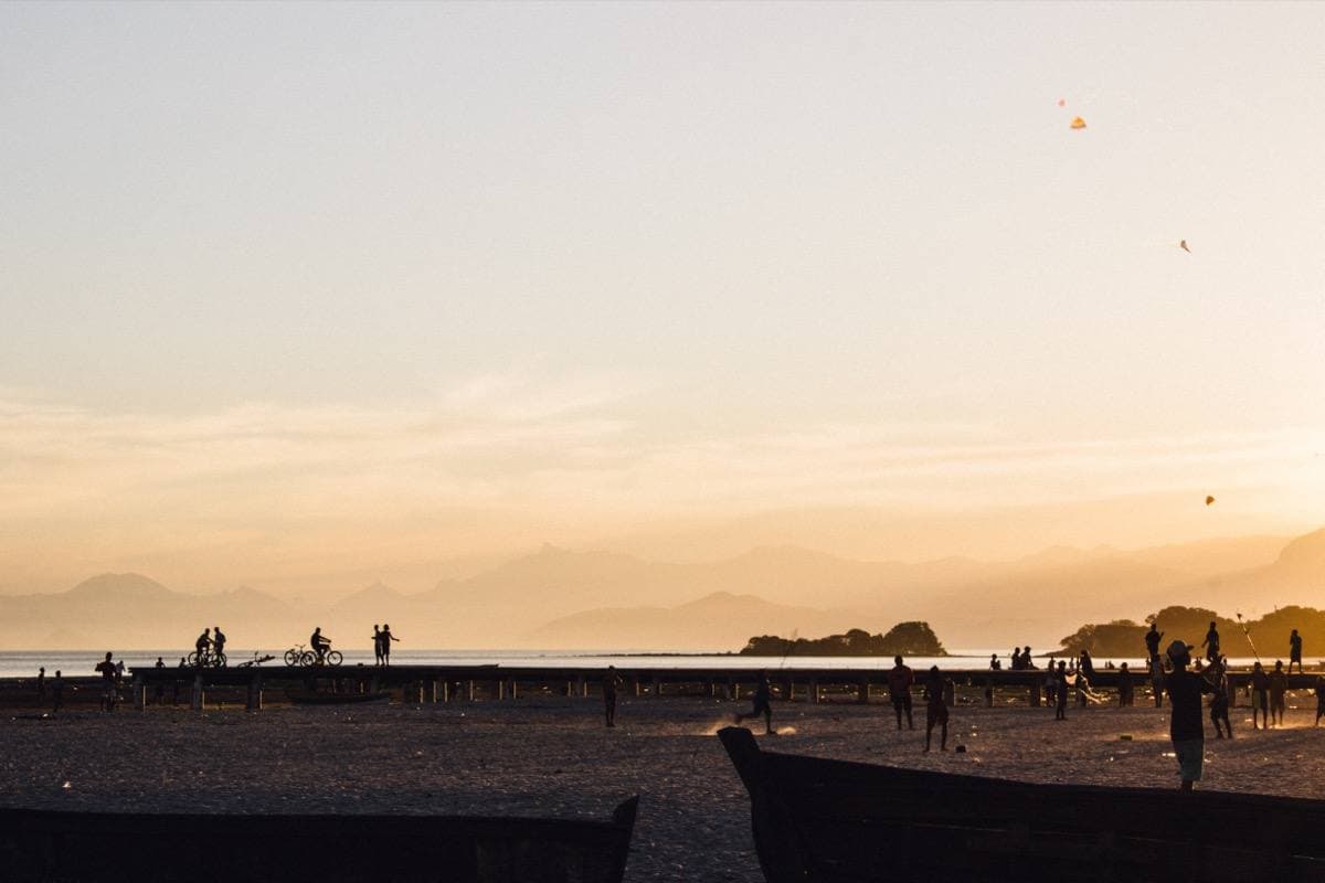 People on Sepetiba beach at sunset with an island and mountains beyond