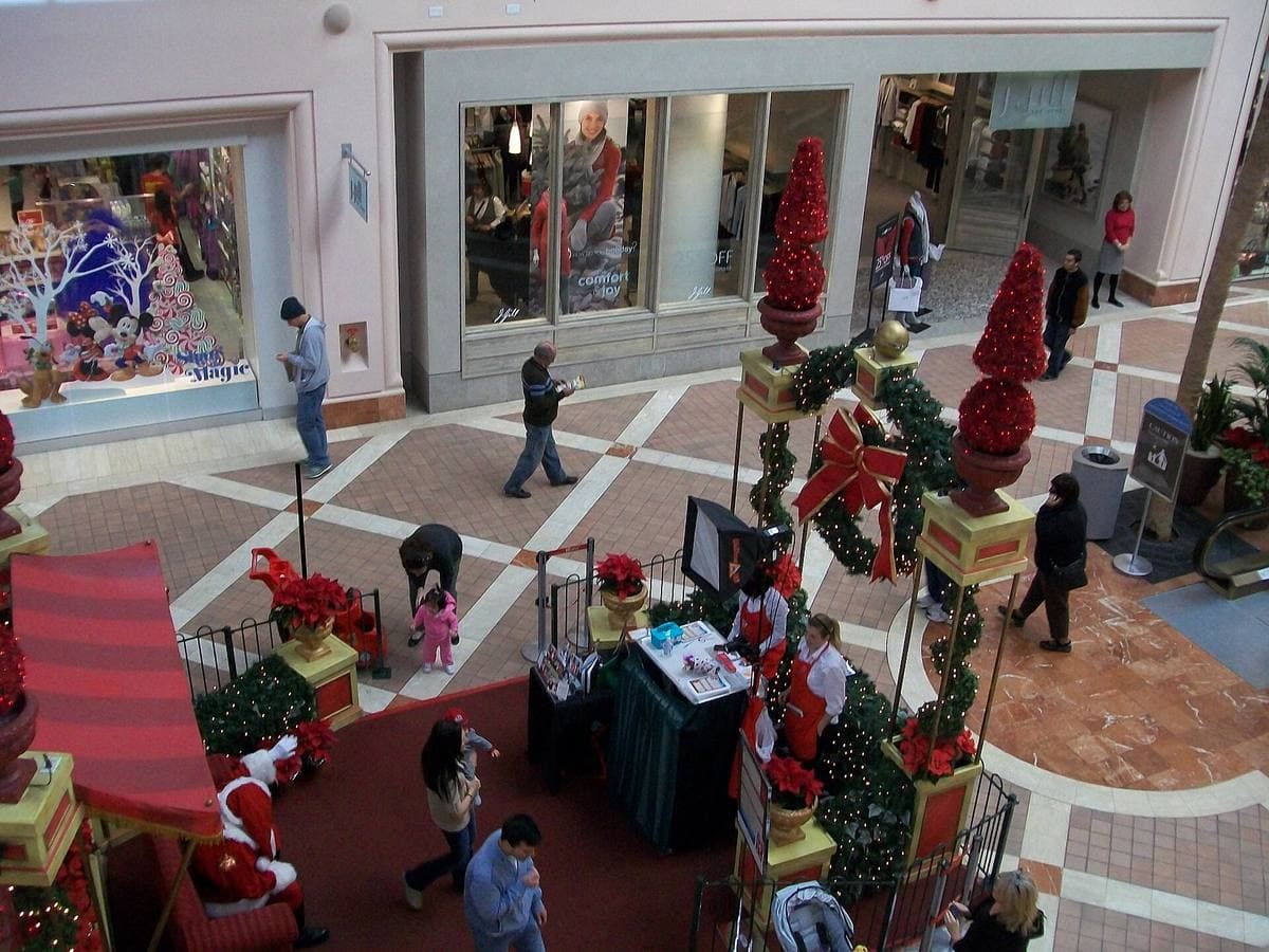 A two-level shopping mall interior with shoppers and decorations