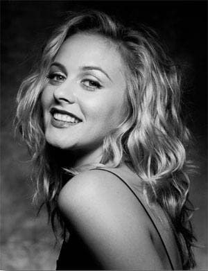 Black-and-white portrait of Alicia Silverstone smiling over her shoulder